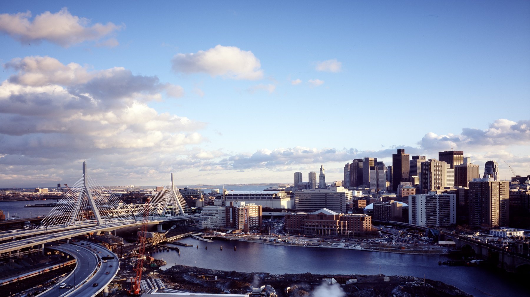 Dusk view of Boston from across the Charles River -- Leonard P. Zakim Bunker Hill Memorial Bridge’s cable-stay towers in the foreground, downtown Financial Dist